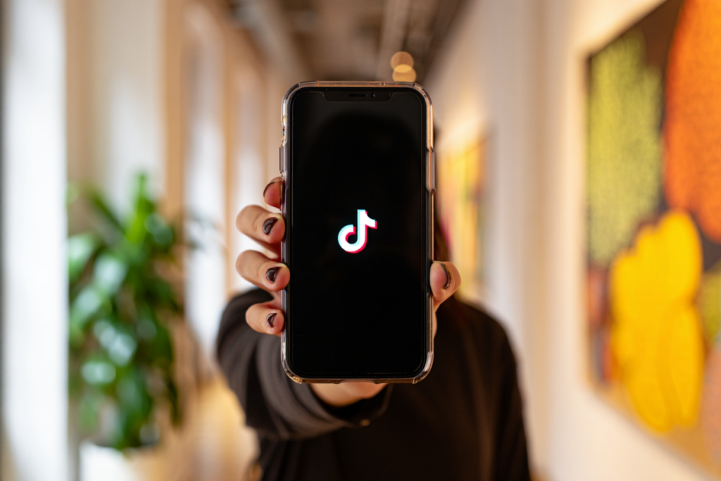 Frau zeigt Logo von TikTok auf einem Smartphone.